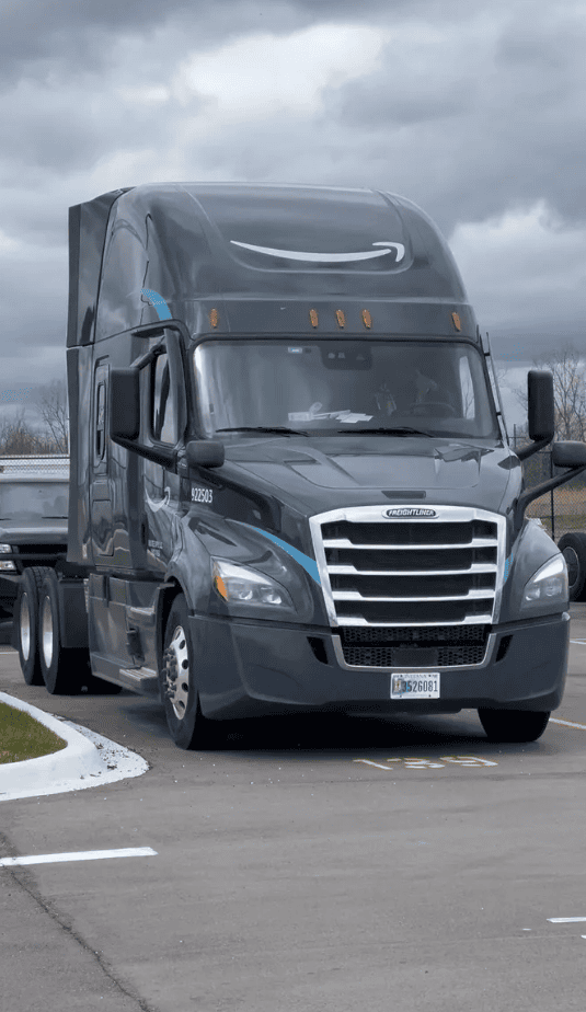 Black semi-truck parked on a cloudy day.